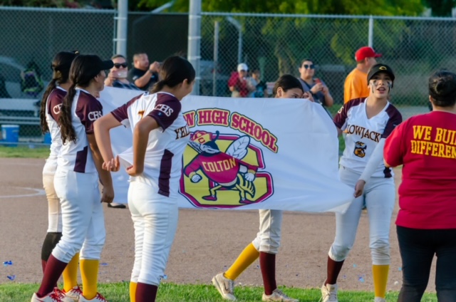 The JV softball team celebrates their final game of the season with a victory banner.