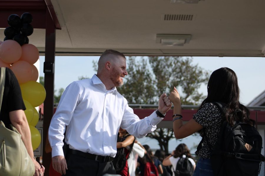 Principal Abbott offers fist bumps to students as they walk through the front gates.