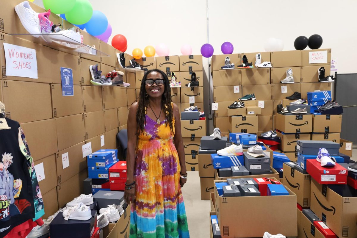 Annette Patterson, founder and Executive Director for the Joshua Home, stands in front of the massive display of brand new shoes donated by Amazon for distribution to local LGBTQ+ youth.