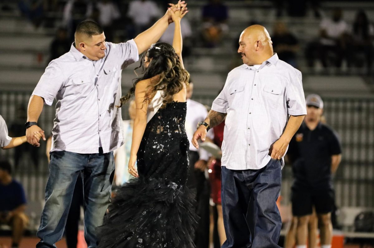 Homecoming Court princess Lisa Lujan is twirled by her brother on the red carpet as she crosses midfield during the halftime festivities.