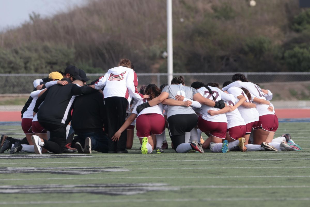 The team takes a knee before the game to pray and contemplate the challenge ahead.