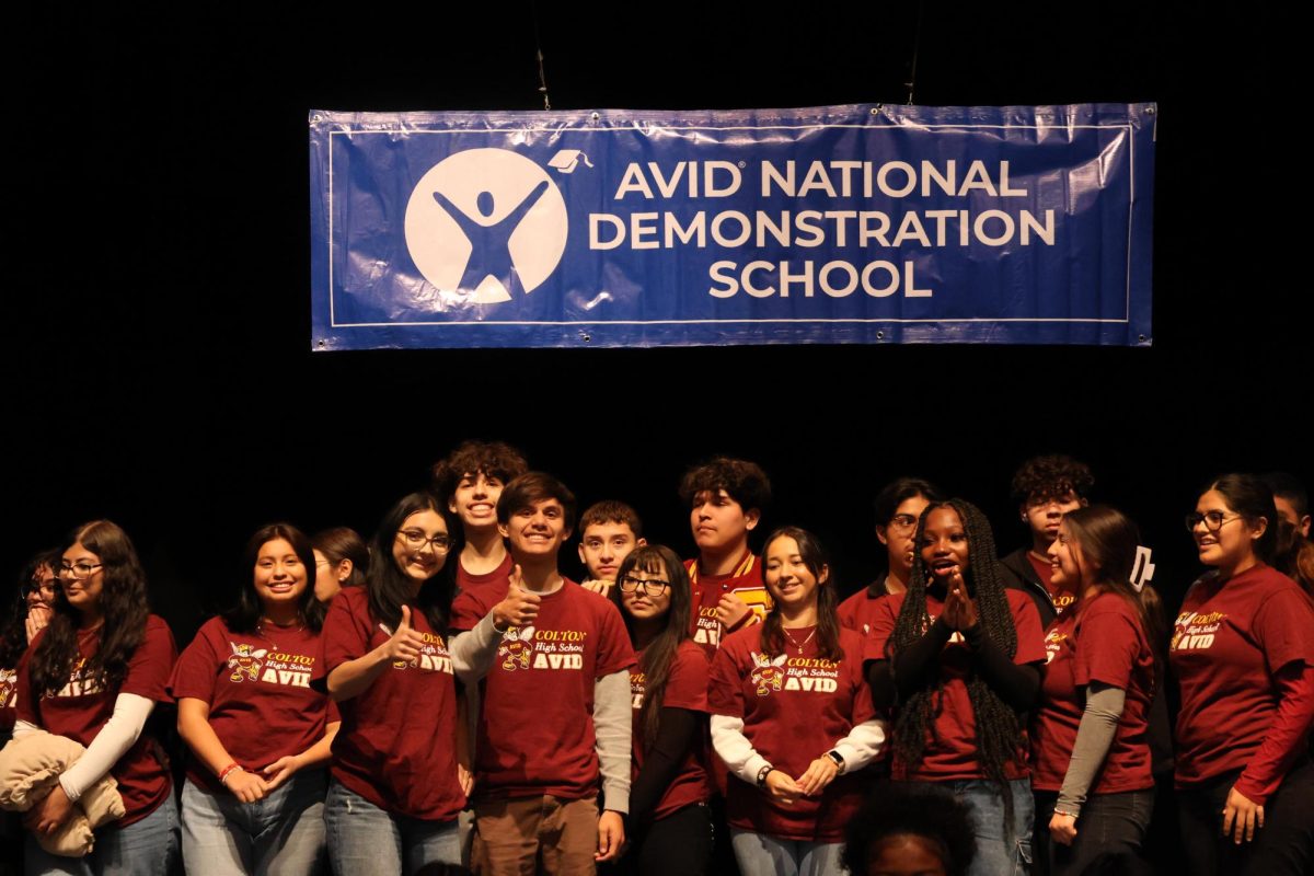 AVID Seniors stand on stage underneath CHSs new National Demonstration Banner. Some ready for the photo, and some still deciding on a pose.