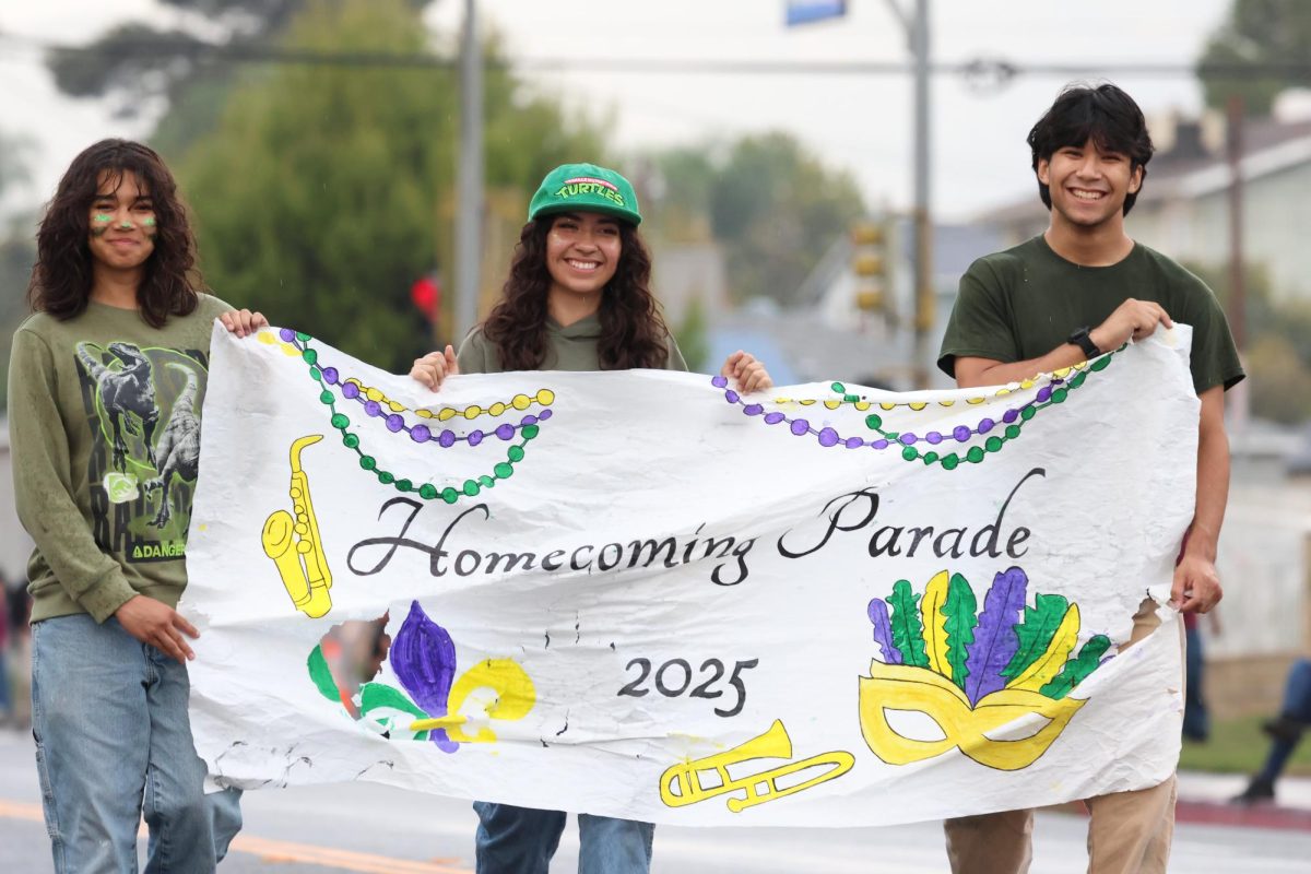 Juniors Tamara Gallardo, Aaria Flores and Uziel Murillo lead the Homecoming Parade with a waterlogged banner, but an undampened spirit.
